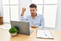 Young handsome man with beard working at the office using computer laptop angry and mad raising fist frustrated and furious while Royalty Free Stock Photo