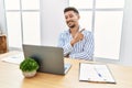 Young handsome man with beard working at the office using computer laptop with a big smile on face, pointing with hand and finger Royalty Free Stock Photo