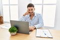 Young handsome man with beard working at the office using computer laptop smiling doing phone gesture with hand and fingers like Royalty Free Stock Photo
