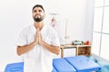 Young handsome man with beard working at pain recovery clinic begging and praying with hands together with hope expression on face Royalty Free Stock Photo