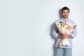 Young handsome man with beautiful flower bouquet on light background Royalty Free Stock Photo