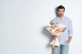 Young handsome man with beautiful flower bouquet on light background, space for Royalty Free Stock Photo