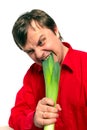 Young handsome man is biting a green leek.