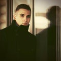 Young handsome man in black coat standing at the window Royalty Free Stock Photo