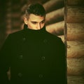 Young handsome man in black coat standing at the wooden cottage Royalty Free Stock Photo