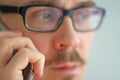 Young handsome man in black glasses is talking on the phone. Closeup portrait of a man. Manager, office worker, talking on the Royalty Free Stock Photo