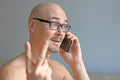 Young handsome man in black glasses is talking on the phone. Closeup portrait of a man. A man shows a sign of victory. Everything Royalty Free Stock Photo