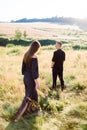 Young handsome man in black shirt and pants waiting for his pretty woman, standing in a field at summer sunset. Back Royalty Free Stock Photo