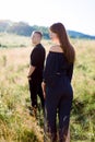 Young handsome man in black shirt and pants waiting for his pretty woman, standing in a field at summer sunset. Back Royalty Free Stock Photo