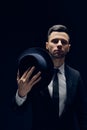 Young handsome man in black suit wearing his hat on dark background