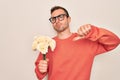 Young handsome man with blue eyes holding bouquet of flowers over white background with angry face, negative sign showing dislike Royalty Free Stock Photo