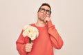 Young handsome man with blue eyes holding bouquet of flowers over white background serious face thinking about question, very Royalty Free Stock Photo