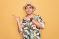 Young handsome man with blue eyes on vacation wearing summer florar shirt and hat amazed and smiling to the camera while Royalty Free Stock Photo