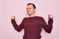 Young handsome man with blue eyes wearing casual sweater standing over pink background very happy and excited doing winner gesture Royalty Free Stock Photo
