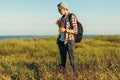 Young handsome man, in a cap and glasses, with a backpack, traveling and walking in nature, a man with a bouquet of wildflowers Royalty Free Stock Photo