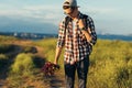 Young handsome man, in a cap and glasses, with a backpack, traveling and walking in nature, a man with a bouquet of wildflowers Royalty Free Stock Photo