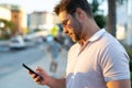 Young handsome man in classik polo t-shirt chatting on phone on the street. Handsome confident stylish hipster model Royalty Free Stock Photo