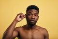 A young handsome man cleans dirty ears with a white cotton swab