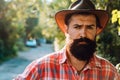 Young handsome man in cowboy hat with long beard, mustache and trendy hairdo.