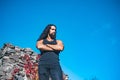 Young handsome man with crossed arms long hair beard, mustache and trendy hairdo outdoor. Royalty Free Stock Photo