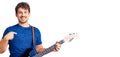 Young handsome man with curly hair playing electric guitar pointing finger to one self smiling happy and proud Royalty Free Stock Photo