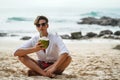 Young handsome man drinking coconut milk on the tropical beach, relaxing. Summer vibes Royalty Free Stock Photo