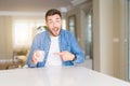 Young handsome man drinking a cup of coffee at home very happy pointing with hand and finger Royalty Free Stock Photo