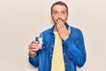 Young handsome man drinking glass of water covering mouth with hand, shocked and afraid for mistake Royalty Free Stock Photo