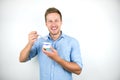 Young handsome man eats yogurt with spoon smiling on isolated white background Royalty Free Stock Photo