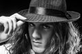 Young handsome man emotional pose with hat. Portrait of handsome young serious confident young guy with long hair in hat Royalty Free Stock Photo