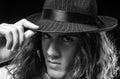 Young handsome man emotional pose with hat. Portrait of handsome young serious confident young guy with long hair in hat Royalty Free Stock Photo