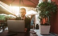 Young handsome man employer in restaurant outdoor with laptop Royalty Free Stock Photo