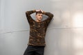 Young handsome man with a fashionable hairstyle in a stylish camouflage shirt in black vintage jeans Royalty Free Stock Photo