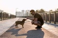 Young handsome man is feeding his dog from hand in the morning on empty street of city Royalty Free Stock Photo
