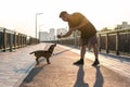 Young handsome man is feeding his dog from hand in the morning on empty street of city Royalty Free Stock Photo