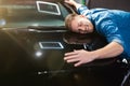 Young handsome man feels happy and joyful hugging his brand new vehicle in electric car dealership center, close up Royalty Free Stock Photo