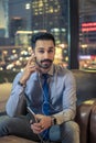 Young handsome man in formal wear listening to music using earphones while sitting on comfortable sofa in modern office. Royalty Free Stock Photo