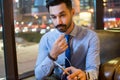 Young handsome man in formal wear listening to music using earphones while sitting on comfortable sofa in modern office Royalty Free Stock Photo