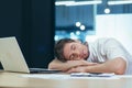 Young handsome man freelancer, businessman, manager in the office at the table resting, fell asleep in his arms at the table, Royalty Free Stock Photo