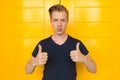 Young handsome man giving thumbs up in front of yellow door Royalty Free Stock Photo