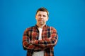 Young handsome man with happy face smiling with crossed arms looking at the camera over blue studio background. Positive person Royalty Free Stock Photo