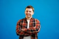 Young handsome man with happy face smiling with crossed arms looking at the camera over blue studio background. Positive person Royalty Free Stock Photo