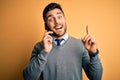 Young handsome man having conversation talking on the smartphone over yellow background surprised with an idea or question Royalty Free Stock Photo