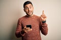 Young handsome man having conversation using smartphone over white background surprised with an idea or question pointing finger Royalty Free Stock Photo