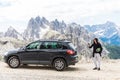 Young handsome man with hiking stuff use phone near his car on mountains background Royalty Free Stock Photo