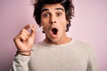 Young handsome man holding aligner standing over isolated pink background scared in shock with a surprise face, afraid and excited Royalty Free Stock Photo