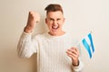 Young handsome man holding Argentinian Argentina flag over isolated white background annoyed and frustrated shouting with anger, Royalty Free Stock Photo