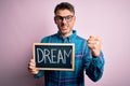 Young handsome man holding blackboard with dream message over pink background annoyed and frustrated shouting with anger, crazy Royalty Free Stock Photo