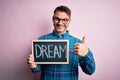 Young handsome man holding blackboard with dream message over pink background happy with big smile doing ok sign, thumb up with Royalty Free Stock Photo