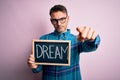 Young handsome man holding blackboard with dream message over pink background pointing with finger to the camera and to you, hand Royalty Free Stock Photo